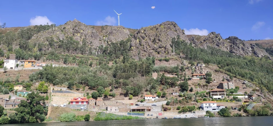 houses on the side of a mountain overlook a body of water