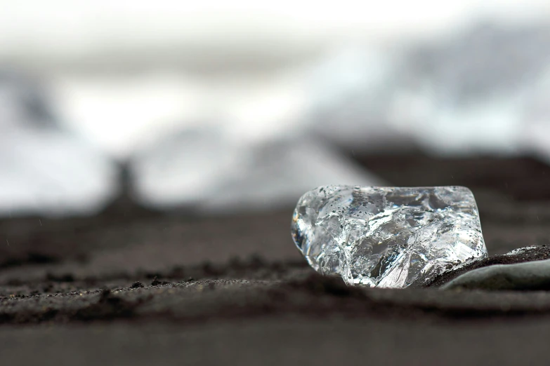 a piece of ice sitting on top of a sand dune