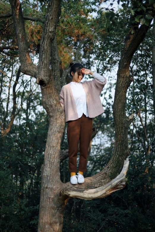 a woman standing on top of a large nch in the middle of a forest