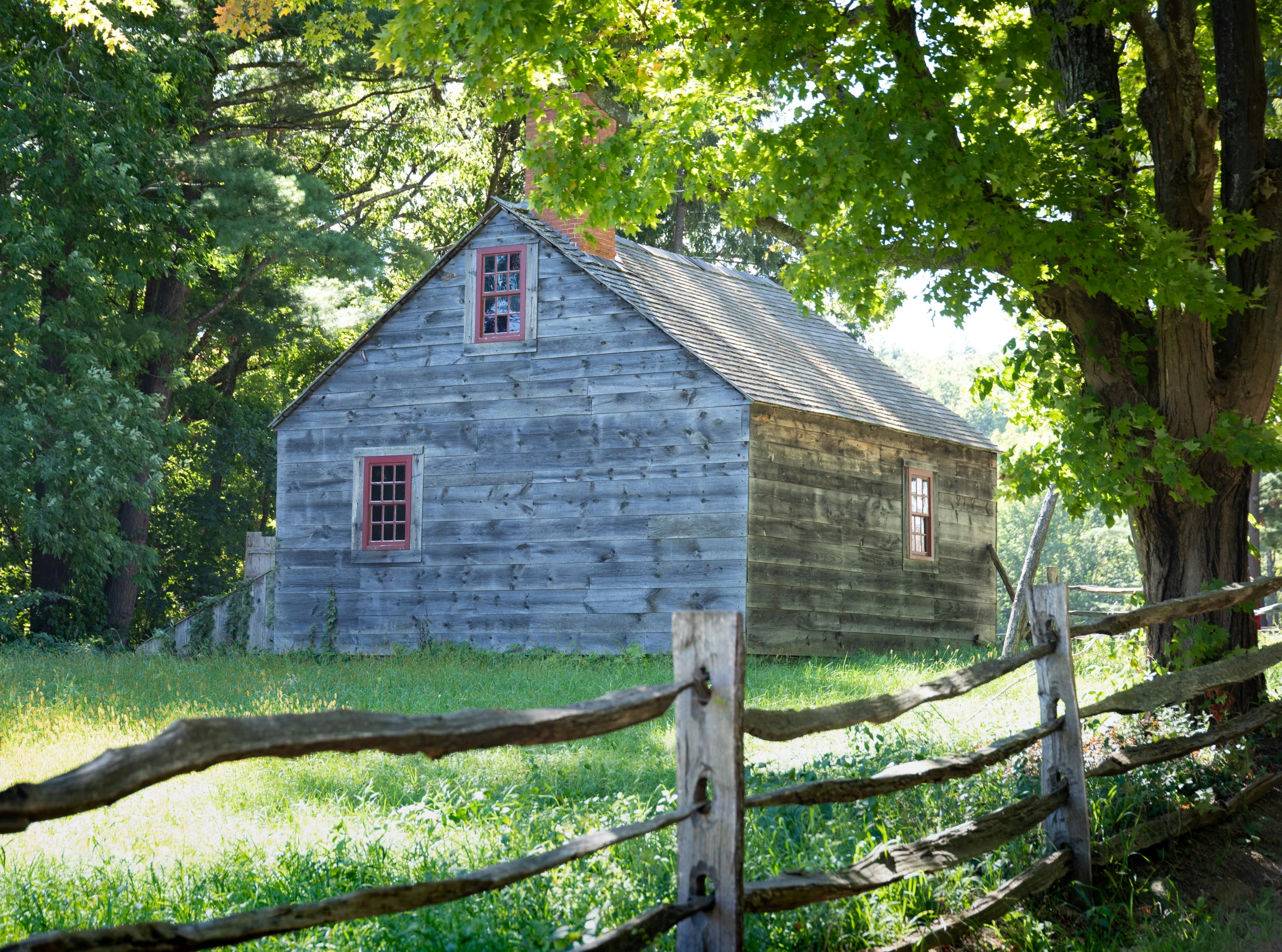 the small wooden barn is beside a split rail fence