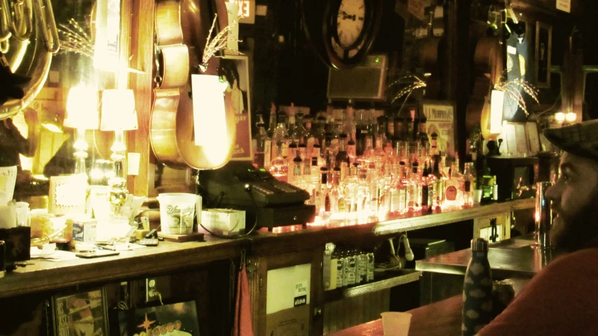 a bar with many bottles of alcohol lit by lights