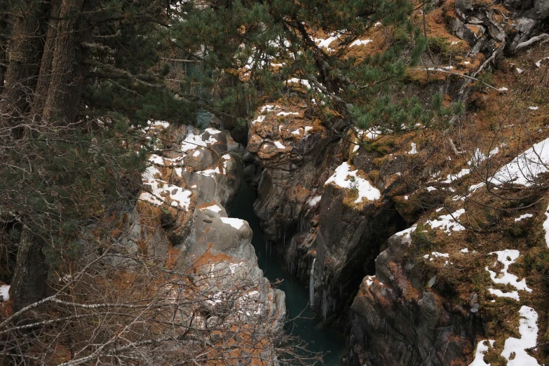 a narrow stream in the middle of a snow covered area