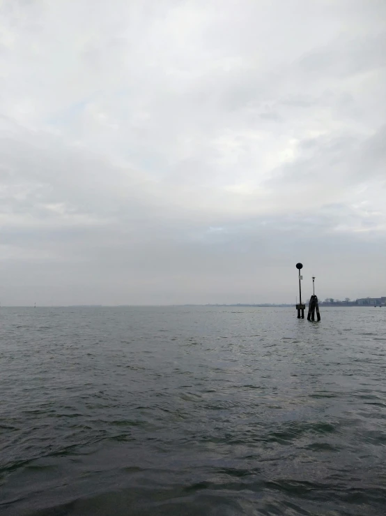 a pier and light on the ocean under cloudy skies