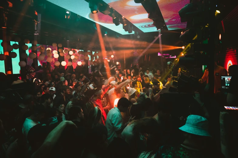 a large crowd of people standing under disco lights