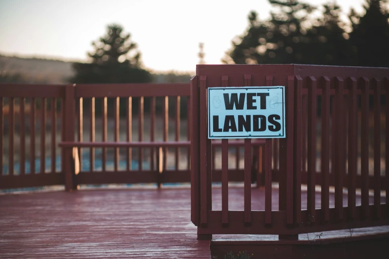 a wet lands sign sitting on top of a red fence