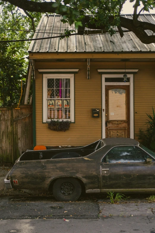 a car parked outside of a small yellow house