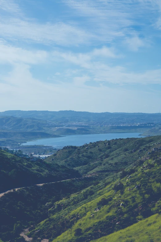 a view of hills, valleys, and large body of water from a hill