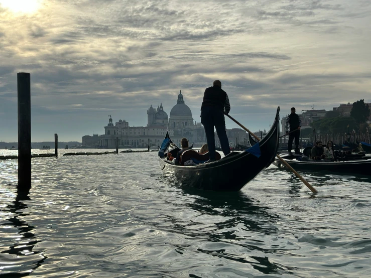 people in gondolas floating in water with buildings in the background