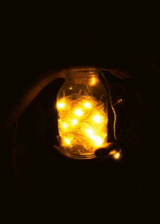 a mason jar filled with yellow lights inside of it