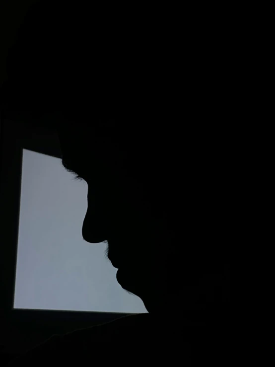 a black silhouette in the dark of a man's face