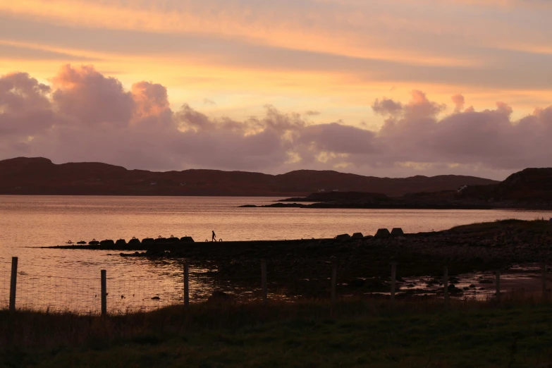 water, mountains and grass during sunset on the coast