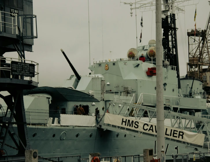 a military ship docked in the water near a crane