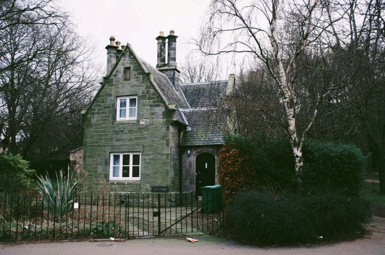 the house is made of stone with a fence and gate