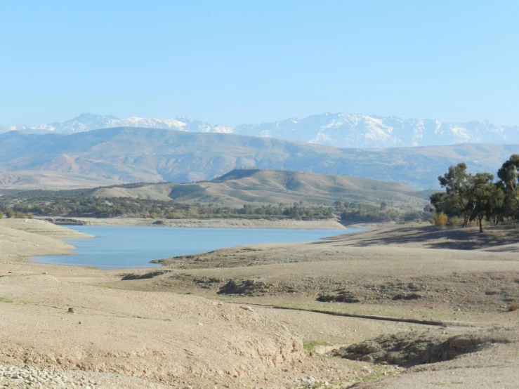 a large body of water sitting in the middle of a dry grass covered field