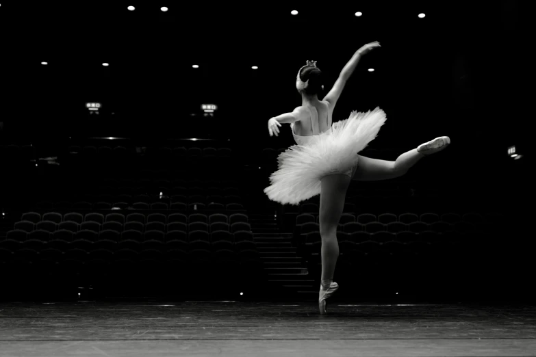 a ballet ballerina wearing white tutu and holding one leg in the air