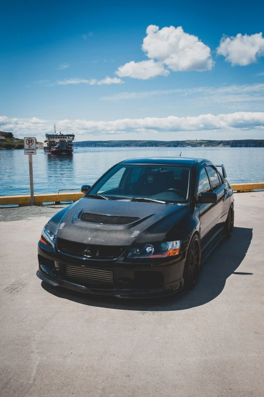 black sport car parked near the sea on the cement