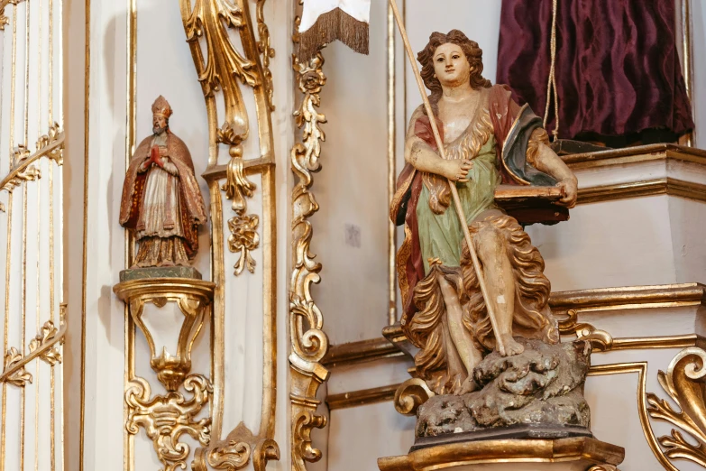 an ornately decorated, gold frame with gold trim and marble figure of a lady on the far end