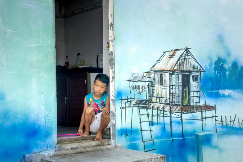 a boy sitting on the steps near the window of a wall