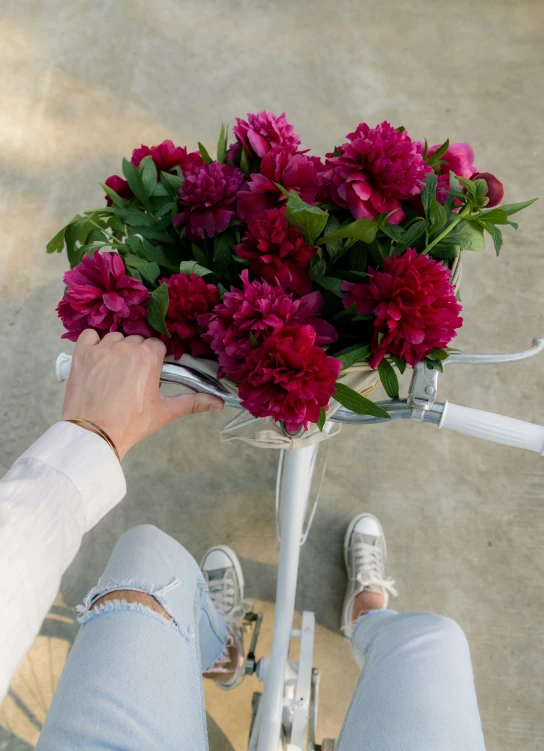 a person holding onto a bunch of flowers on a bike