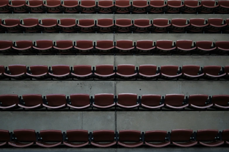 rows of red seats sit on top of a cement wall