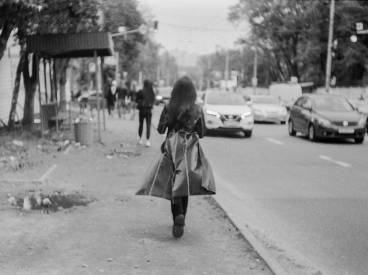 an old black and white po shows a woman walking down the street in her dress