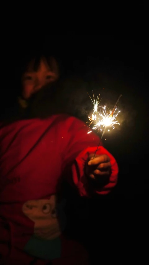 a person holding a lit sparkler in the dark