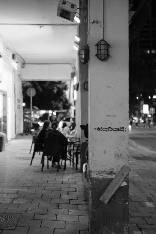 people sitting at tables in a restaurant on the sidewalk