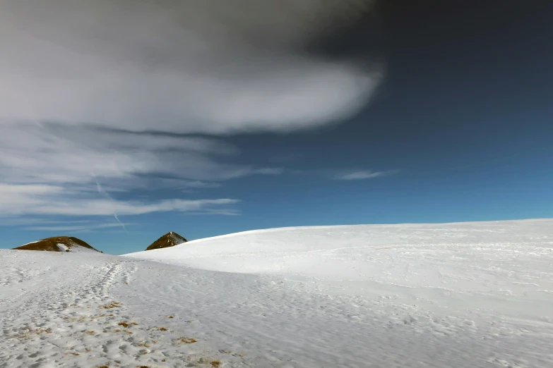 a snow covered ski slope under a cloudy blue sky