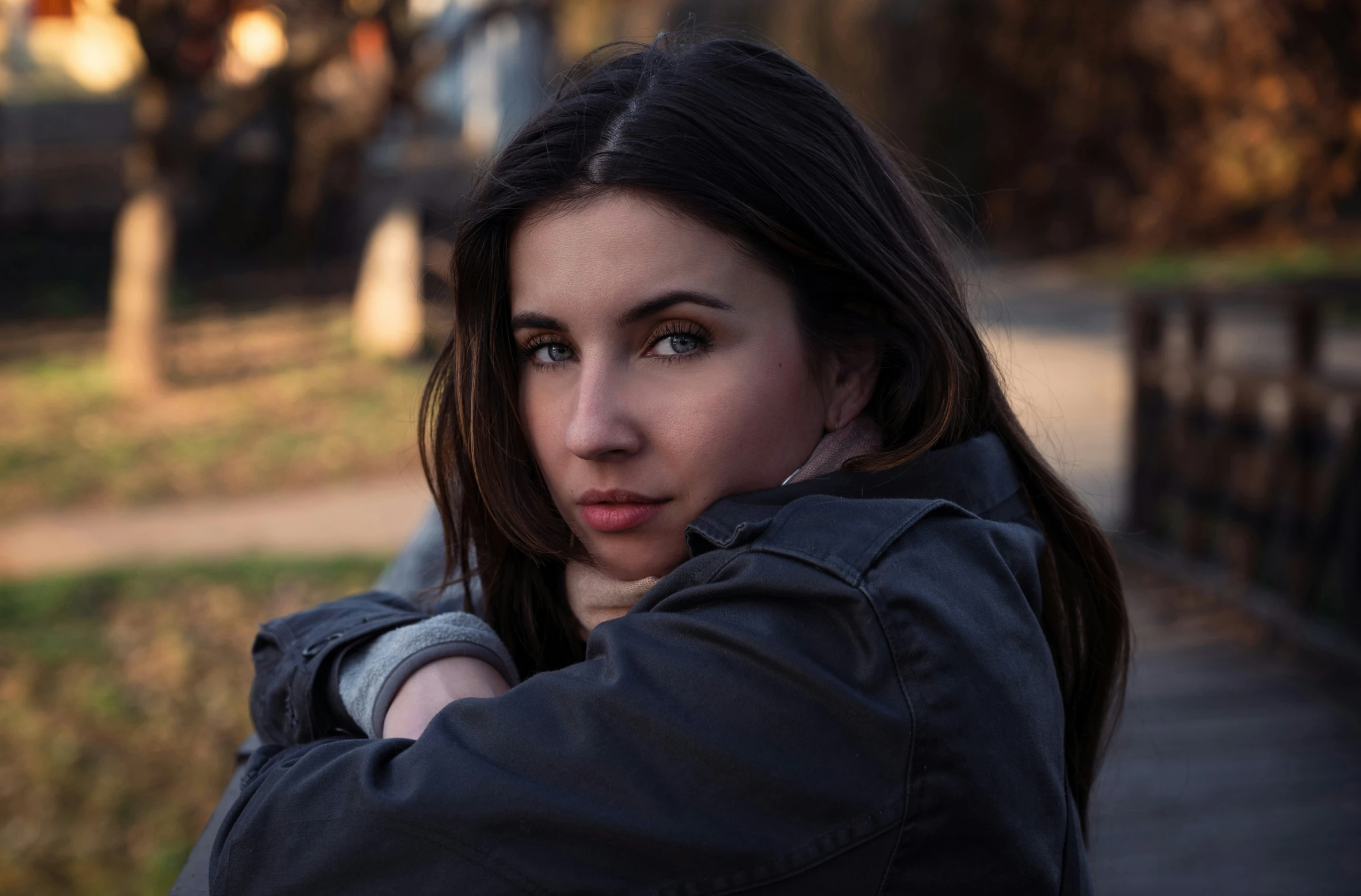 a girl in gray jacket leaning against wooden wall