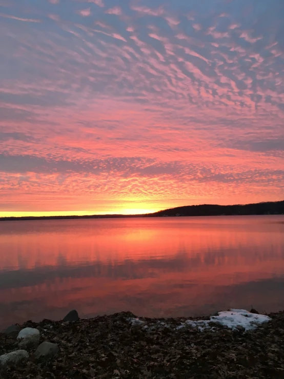 a body of water at sunset with a mountain range in the background