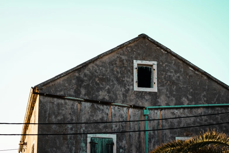 a barn with a large open window next to a palm tree