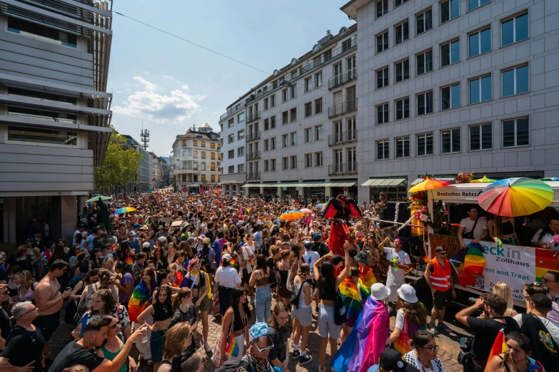 the people are standing in the crowded area with umbrellas