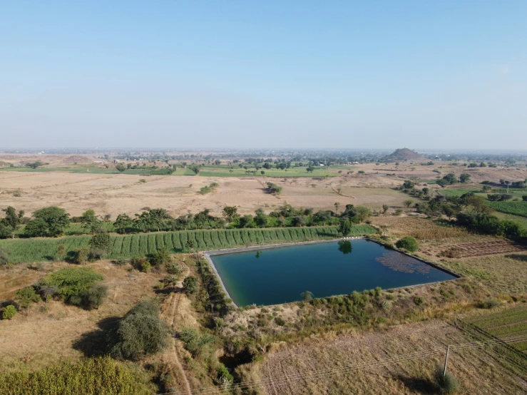 a pond surrounded by trees and other farmland