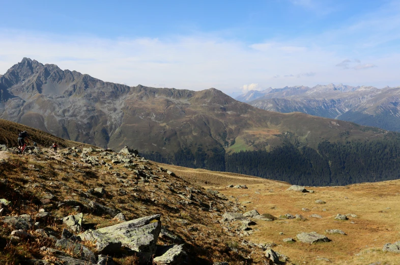 a couple of people walking along a rocky hill