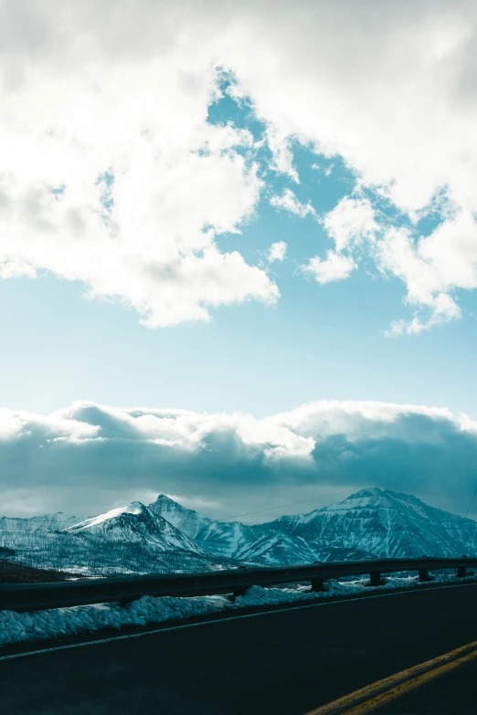 a bus drives on the highway below snow - capped mountains