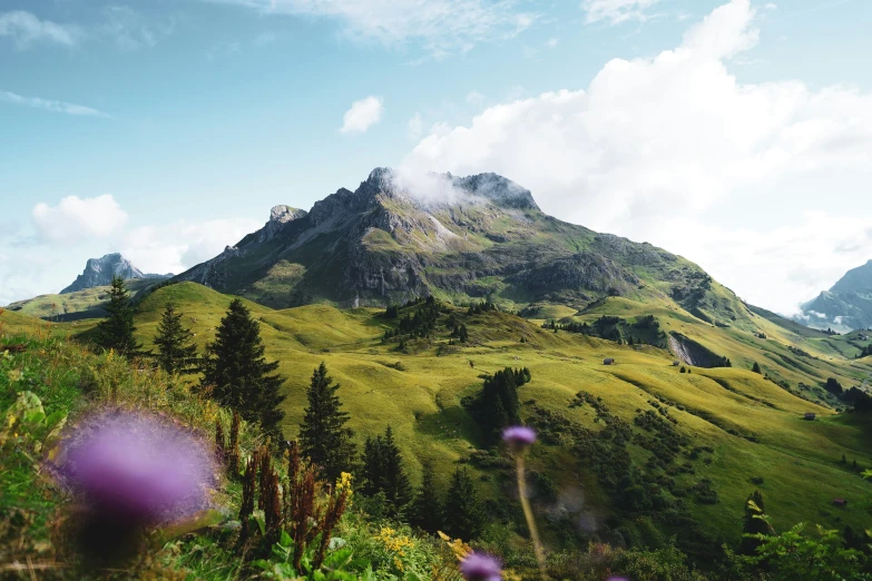 a mountain covered in lush green mountains under a cloudy sky