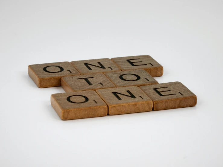 two wooden scrabble tiles spelling the words one to one