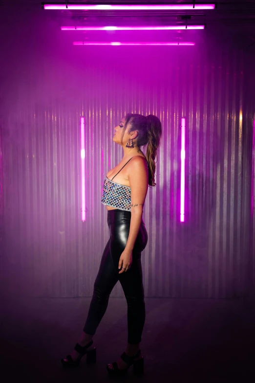 a woman in a  - top standing next to a neon backdrop