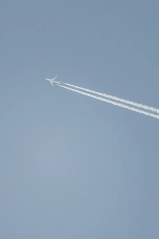 an airplane flying through the sky with contrails in front of it