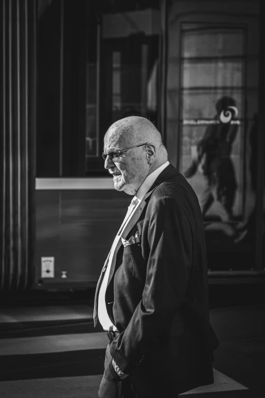 a man wearing glasses on the street with his back to the camera