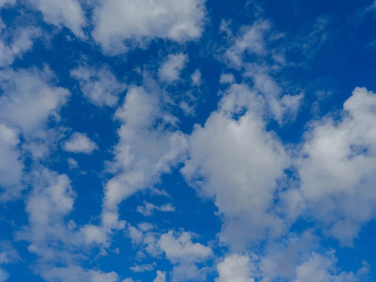 an airplane flying in the cloudy blue sky