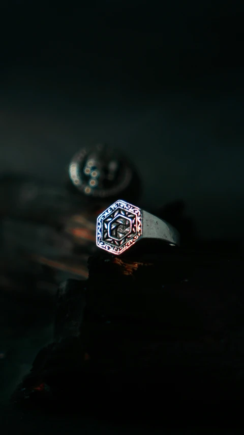 a unique ring sits in the dark, against dark background