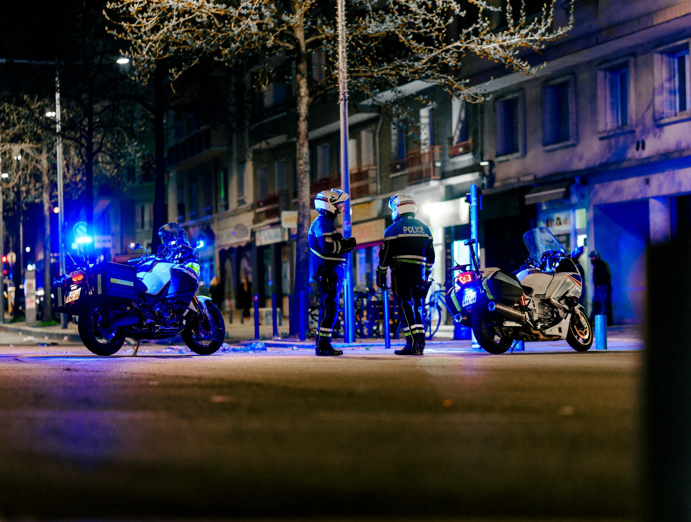 three police officers standing next to a motorcycle on a street