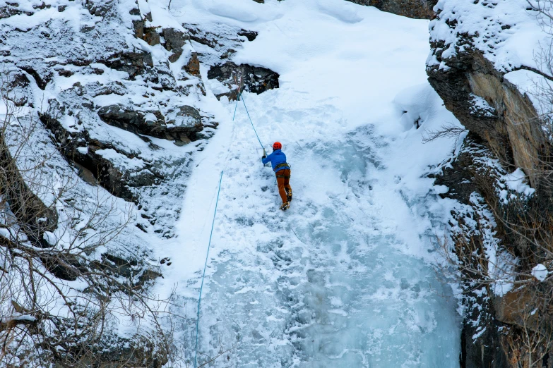 the man is on the side of a big ice cave