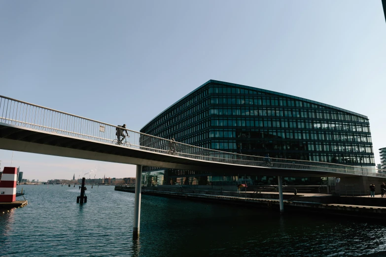 a boat floating past a large glass building on top of water