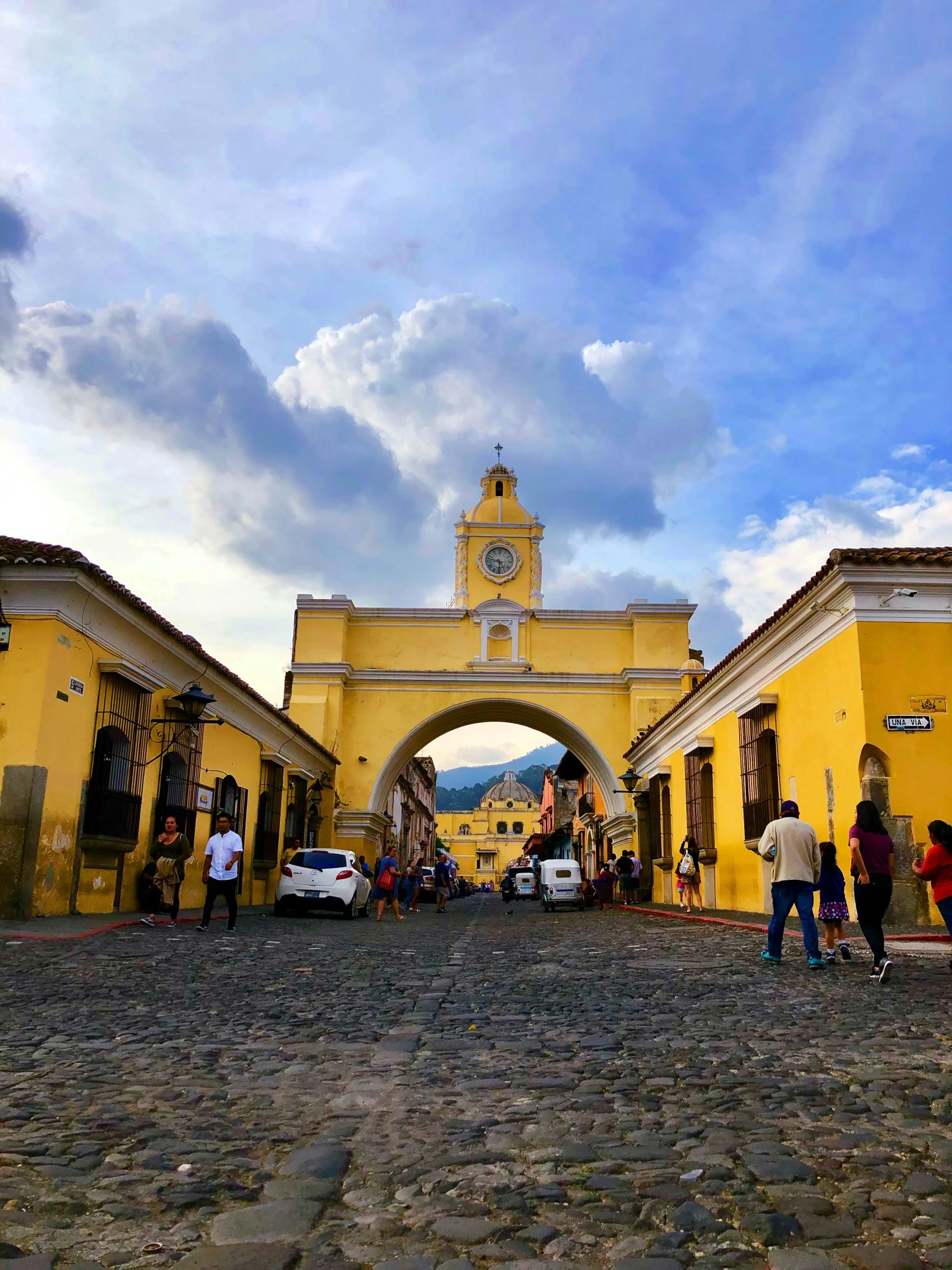 people are walking in front of yellow buildings and an arch