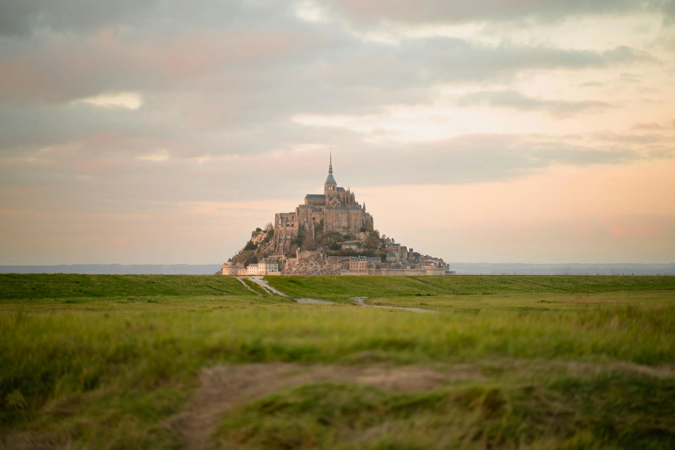 the castle is surrounded by grass and an orange sky