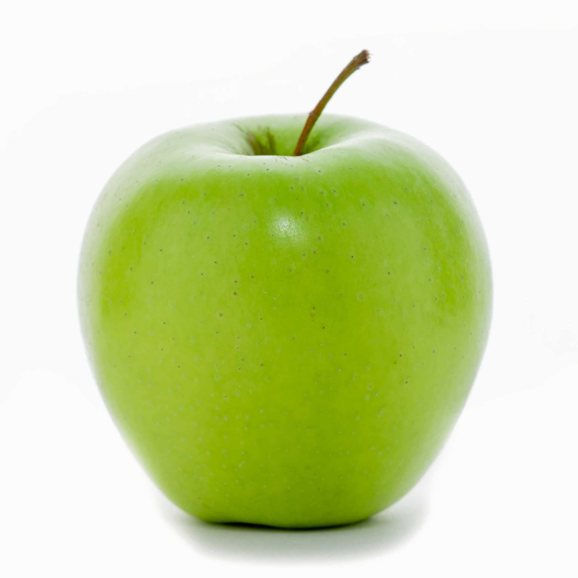 a large green apple sitting on top of a white table