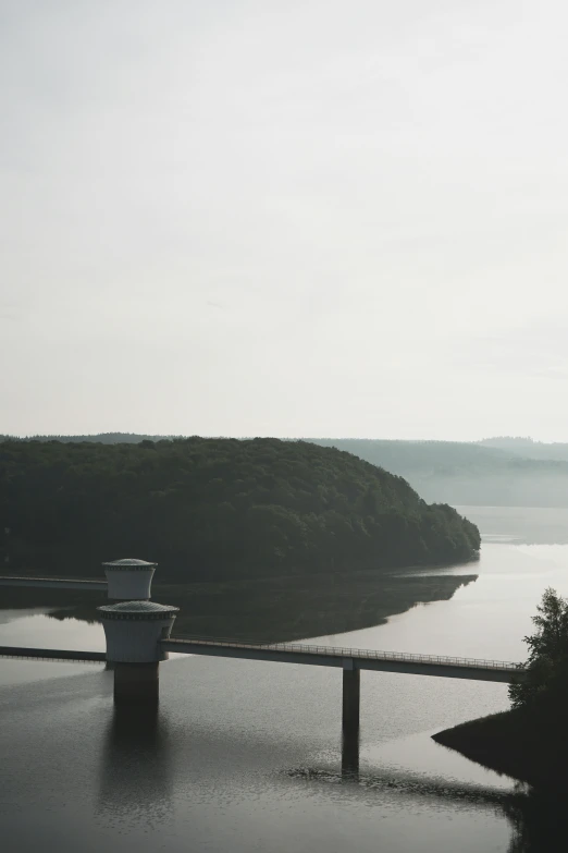 a bridge with water in front of it and hills on the other side