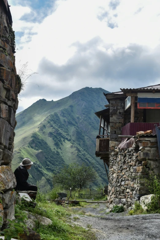 a person sitting outside by some buildings on the mountains